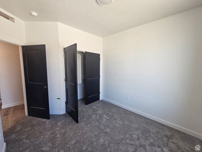 Unfurnished bedroom featuring dark colored carpet, baseboards, and a closet | Image 24