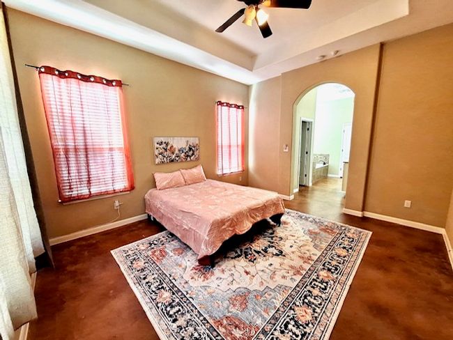Master Bedroom featuring arched walkways, a raised ceiling, baseboards, and multiple windows | Image 9
