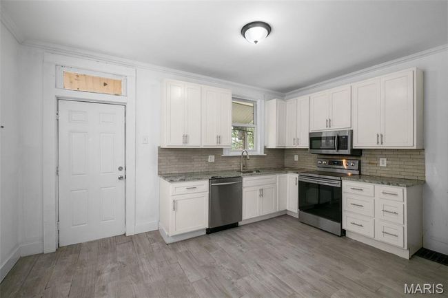 Kitchen featuring appliances with stainless steel finishes, tasteful backsplash, light stone counters, and crown molding | Image 9