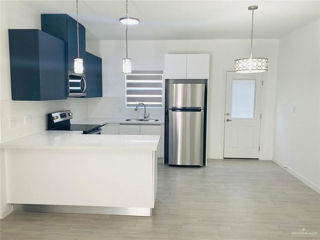 Kitchen with stainless steel appliances, light wood-style floors, light countertops, and pendant lighting | Image 5