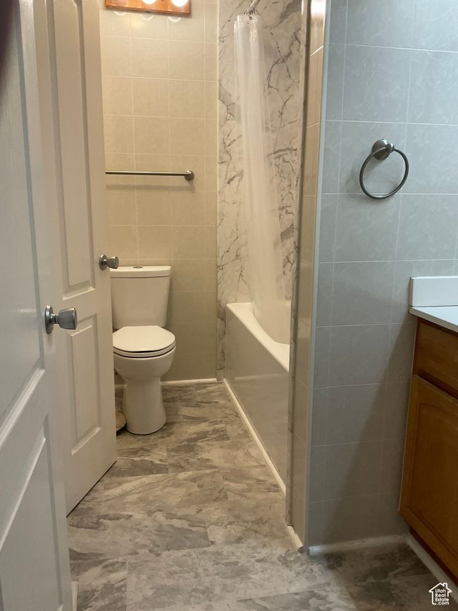 Full bathroom with shower / tub combo, vanity, tile walls, and toilet | Image 13