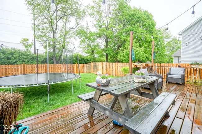 wooden terrace featuring a trampoline and outdoor dining space | Image 5