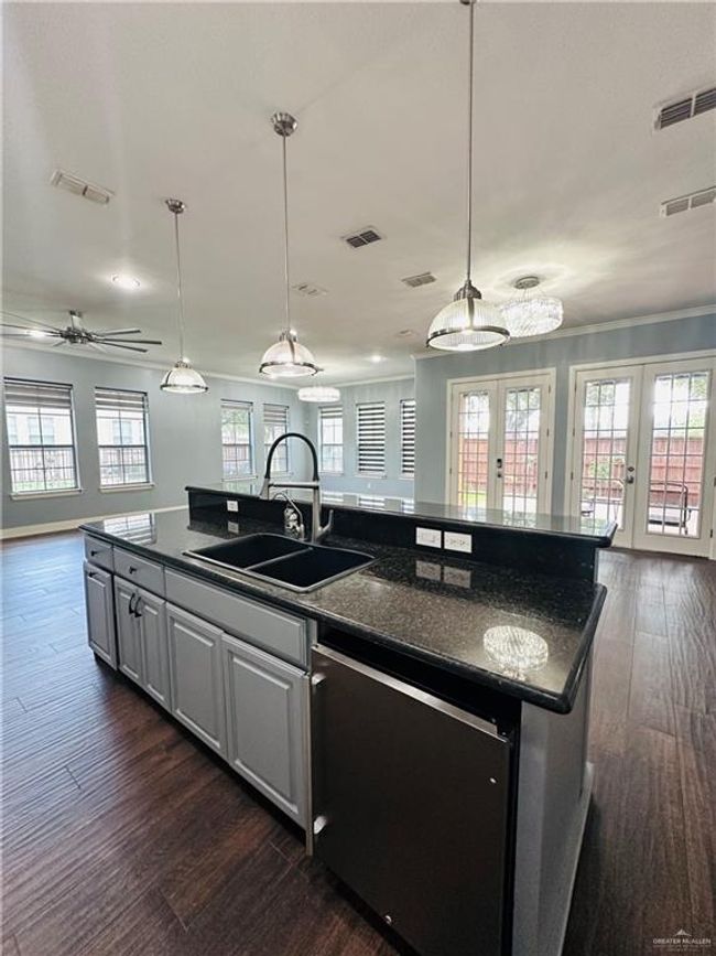 Kitchen with open floor plan, french doors, dark wood-style flooring, a kitchen island with sink, and recessed lighting | Image 7