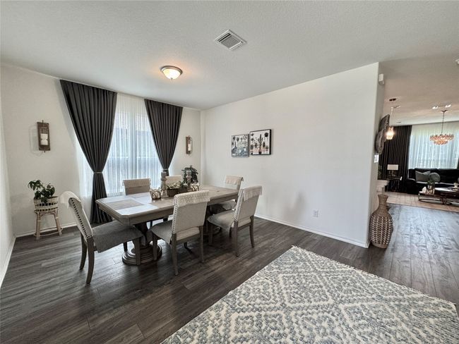 Dining room with dark wood-type flooring, a chandelier, and a textured ceiling | Image 5