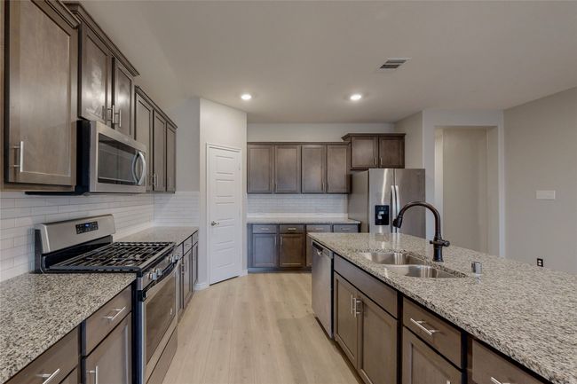 Kitchen featuring a sink, dark brown cabinetry, visible vents, light wood-style flooring, and appliances with stainless steel finishes | Image 14