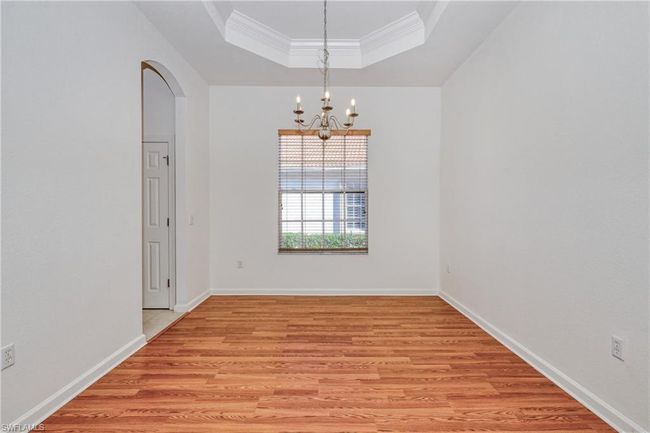 Spare room with crown molding, a tray ceiling, an inviting chandelier, and light wood-type flooring | Image 17