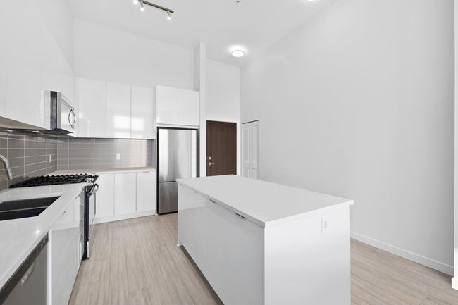 Kitchen featuring modern cabinets, a center island, white cabinetry, and appliances with stainless steel finishes | Image 10