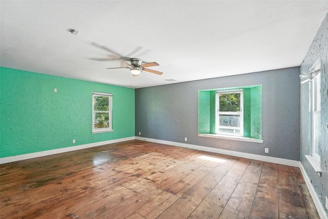 Unfurnished room featuring plenty of natural light, a textured wall, a ceiling fan, and wood-type flooring | Image 26