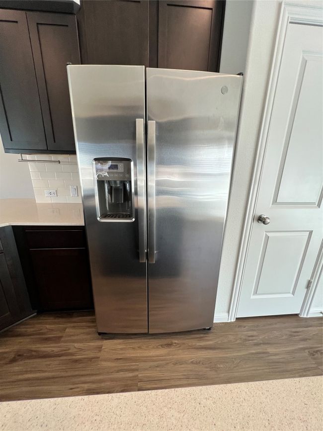 Kitchen featuring stainless steel fridge with ice dispenser, backsplash, dark brown cabinetry, and dark wood-style flooring | Image 14