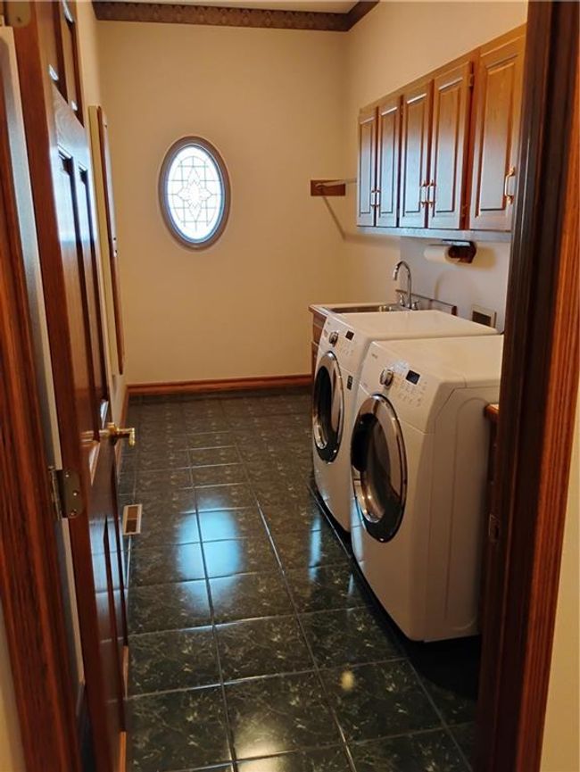 Washroom featuring a sink, dark tile patterned floors, baseboards, washer and dryer, and cabinet space | Image 37