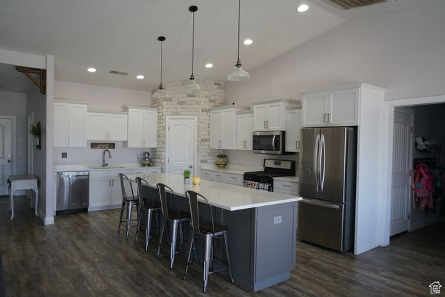 Kitchen featuring stainless steel appliances, a center island, a breakfast bar, a sink, and white cabinets | Image 5