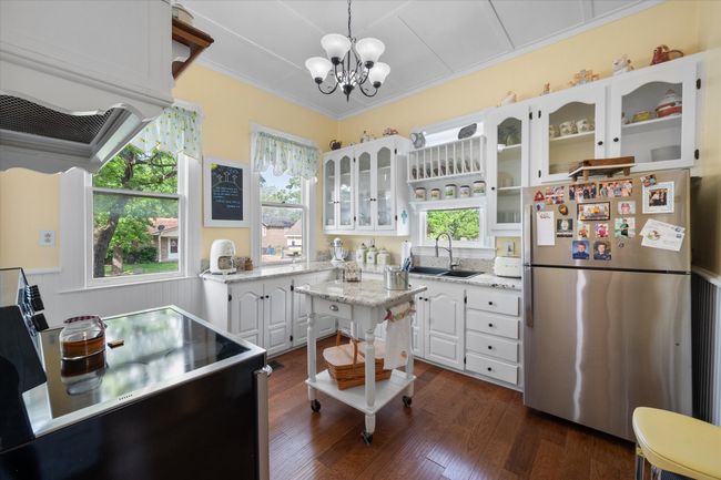 Kitchen with freestanding refrigerator, a sink, range, white cabinets, and a chandelier | Image 14