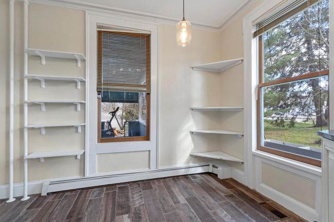 Detailed view of crown molding, wood finished floors, and baseboard heating | Image 19