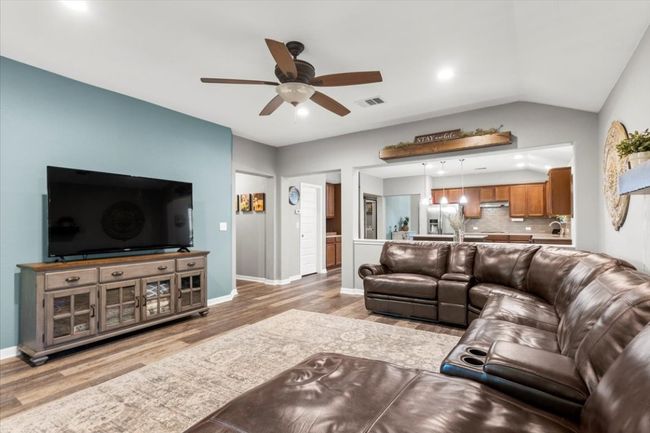 Living room featuring a ceiling fan, light wood laminate floors, baseboards, lofted ceiling, and recessed lighting | Image 13