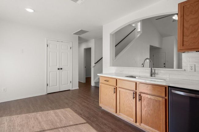 Kitchen featuring dark wood-style flooring, light countertops, visible vents, dishwasher, and a sink | Image 9