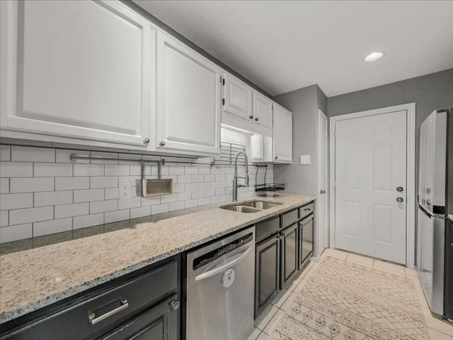 Kitchen featuring refrigerator, white cabinetry, dishwasher, sink, and light stone countertops | Image 13