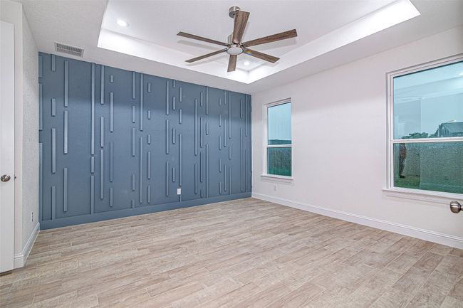 Spare room with a tray ceiling, a ceiling fan, light wood-style floors, baseboards, and recessed lighting | Image 21