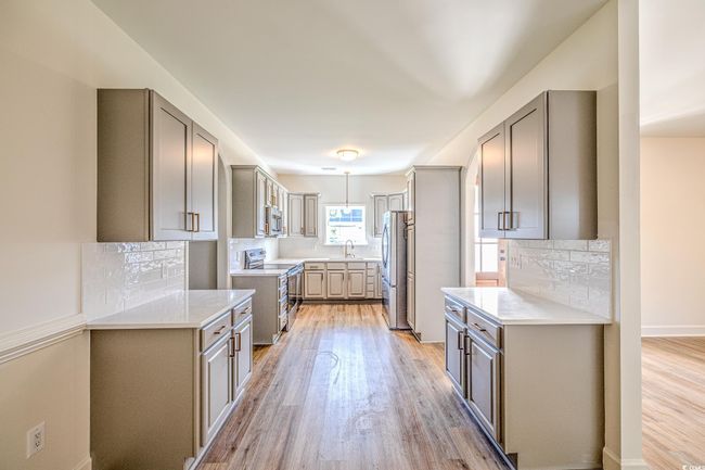 Kitchen with stainless steel appliances, gray cabinetry, light wood-style flooring, and backsplash | Image 26