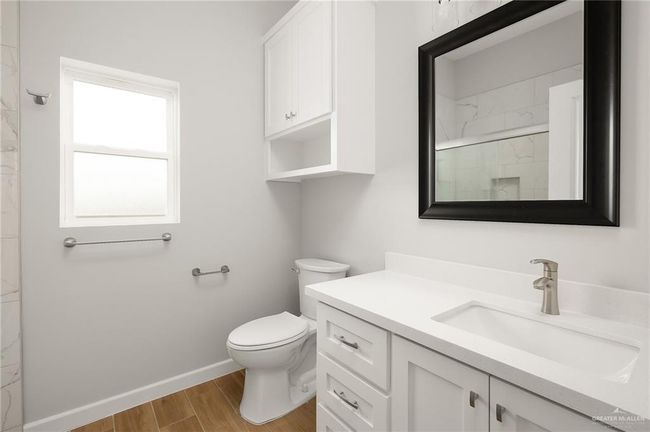 Bathroom with baseboards, toilet, vanity, wood finished floors, and a marble finish shower | Image 11