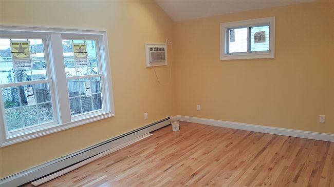Spare room with vaulted ceiling, baseboard heating, light hardwood / wood-style floors, and a wall mounted air conditioner | Image 10