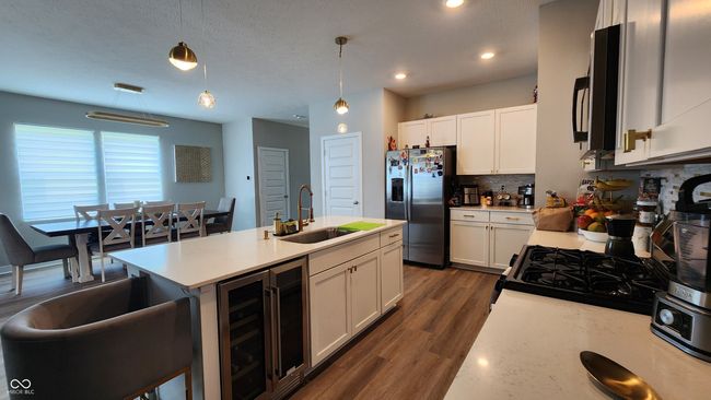 kitchen with stainless steel fridge, wine cooler, light countertops, tasteful backsplash, and recessed lighting | Image 7
