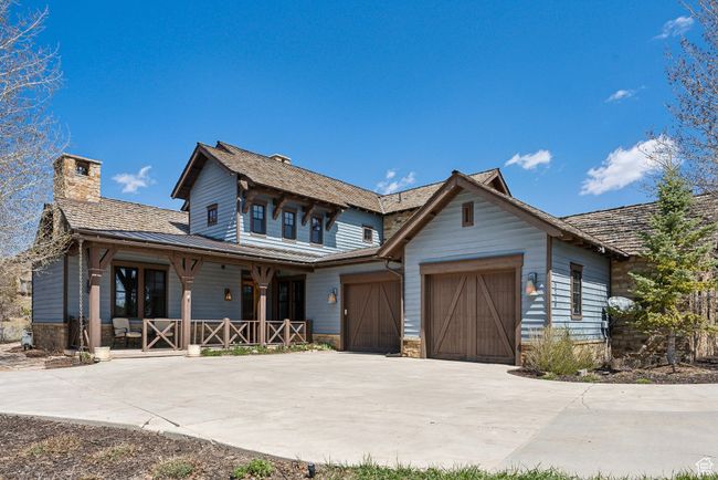View of front of house with stone siding, a garage, a chimney, covered porch, and driveway | Image 30