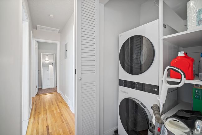 Laundry room with stacked washer and clothes dryer, attic access, and light wood-type flooring | Image 12