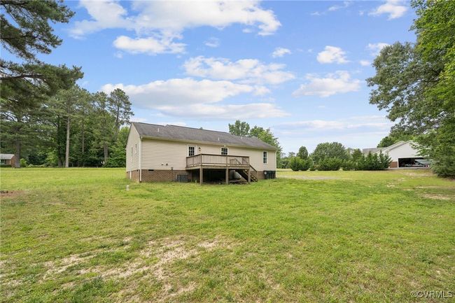 Rear view of property featuring a wooden deck, a lawn, crawl space, and central AC unit | Image 31