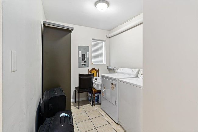 Washroom with light tile patterned floors, electric panel, laundry area, and washer and clothes dryer | Image 32