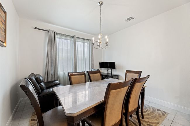 Formal dining area featuring light tile floors, a notable chandelier, French doors | Image 5