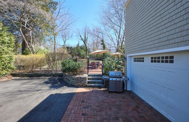View of patio / terrace featuring aphalt driveway, fence, grilling area, and a garage | Image 31