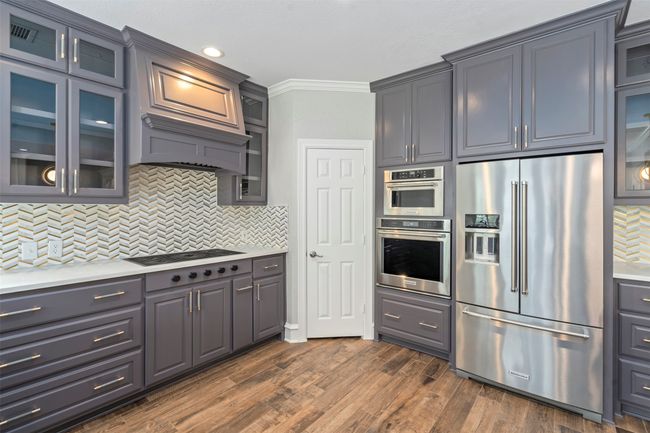 Kitchen with stainless steel appliances, light countertops, tasteful backsplash, crown molding, and dark wood-type flooring | Image 4