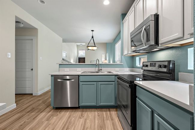 The kitchen is equipped with modern quartz countertops, a Bosch dishwasher, and ample cabinet space, making it a practical and stylish spot for preparing meals or entertaining | Image 4