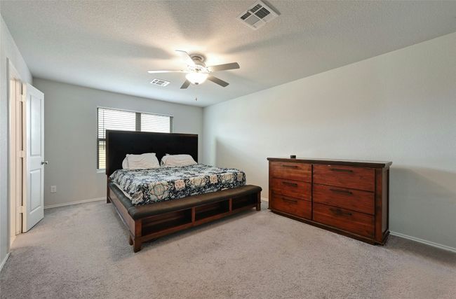 Bedroom with light colored carpet, a textured ceiling, and ceiling fan | Image 4