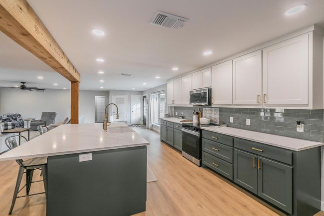 Kitchen featuring appliances with stainless steel finishes, white cabinets, backsplash, light wood-style flooring, and recessed lighting | Image 6