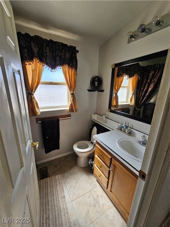 Bathroom with toilet, vanity, visible vents, and a wealth of natural light | Image 19