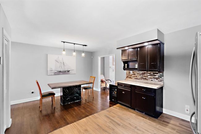 Kitchen featuring hanging light fixtures, light countertops, dark brown cabinets, light wood-style floors, and backsplash | Image 17
