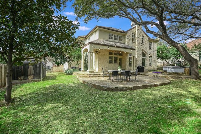 Back of house with stucco and Limestone siding, a large flat lawn, a hot tub, a patio area, and privacy fence | Image 33