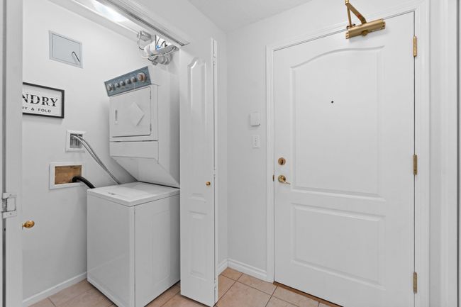 Laundry room featuring stacked washer and clothes dryer, light tile patterned floors, and baseboards | Image 13