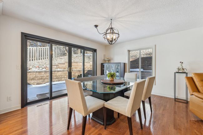 Bright dining area with glass sliding doors and a large window, offering access to the backyard and views of the terraced landscaping. | Image 9