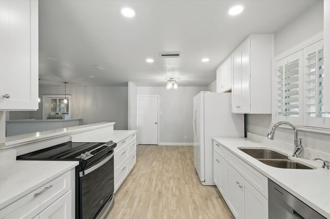 Kitchen featuring white cabinets, range with electric stovetop, visible vents, stainless steel dishwasher, and a sink | Image 10