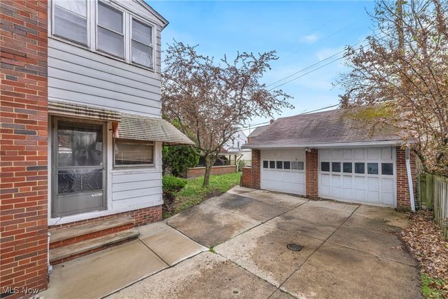View of side of home with entry steps, an outbuilding, brick siding, and a detached garage | Image 47