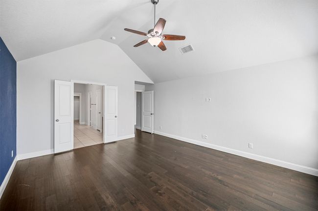 Unfurnished bedroom featuring visible vents, high vaulted ceiling, wood finished floors, baseboards, and ceiling fan | Image 25