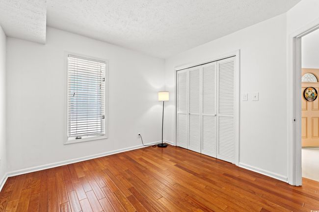 Unfurnished bedroom with a textured ceiling, wood-type flooring, and a closet | Image 19