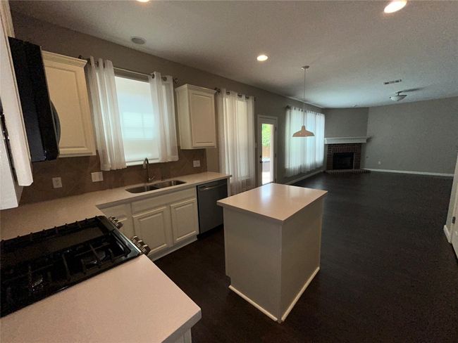 Kitchen featuring stainless steel dishwasher, a sink, a center island, recessed lighting, and light countertops | Image 13