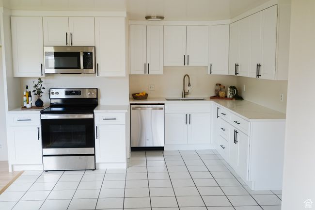 Kitchen featuring appliances with stainless steel finishes, light countertops, and white cabinetry | Image 8