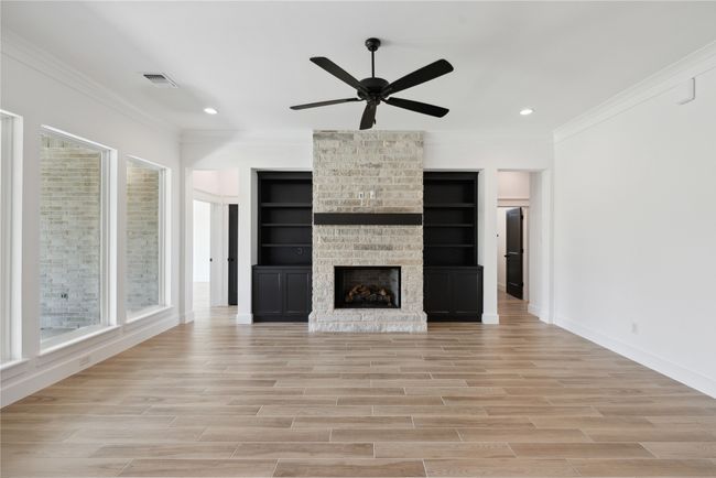 Unfurnished living room featuring ornamental molding, a large fireplace, and light wood-type flooring | Image 8