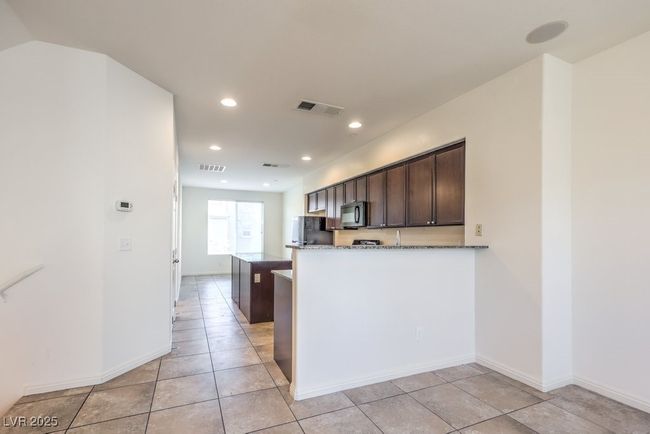 Kitchen featuring black appliances, dark stone countertops, visible vents, and dark brown cabinetry | Image 16