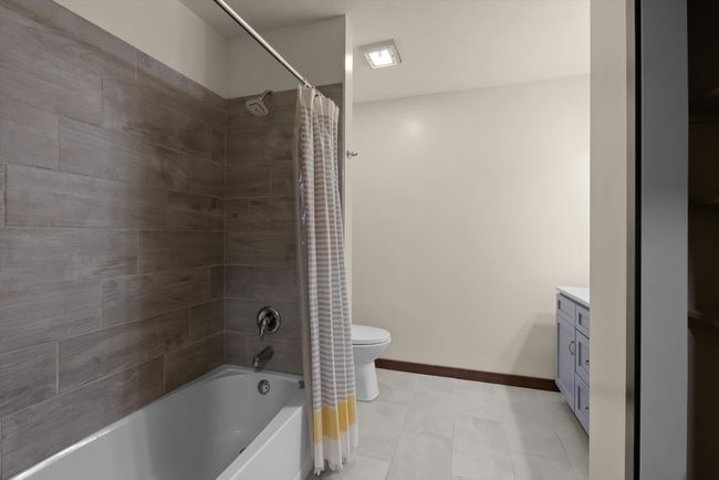 Full bath with toilet, shower / bathtub combination with curtain, vanity, and baseboards | Image 25