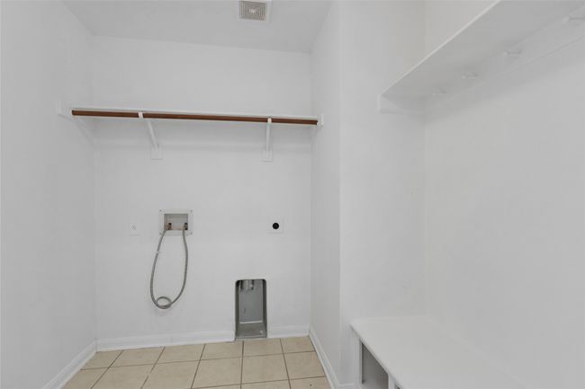 Laundry area featuring hookup for a washing machine, hookup for an electric dryer, and light tile patterned floors | Image 23